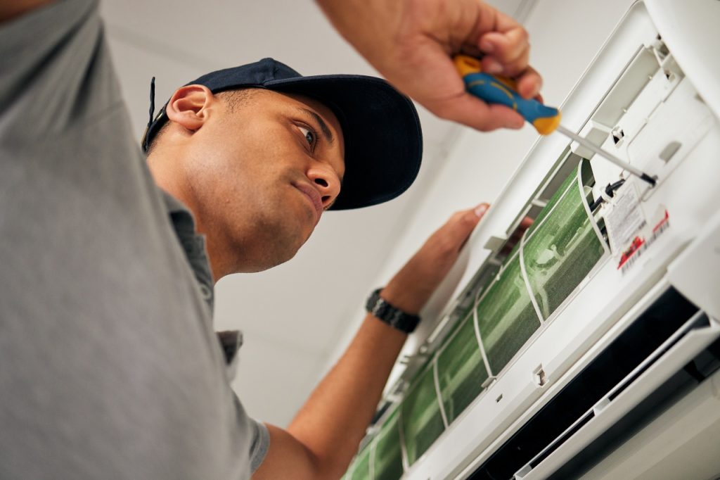 A professional technician handles the baseline positioning and alignment of an air handler unit, demonstrating a precise installation process that directly factors into the total AC repair cost in the Florida Panhandle.