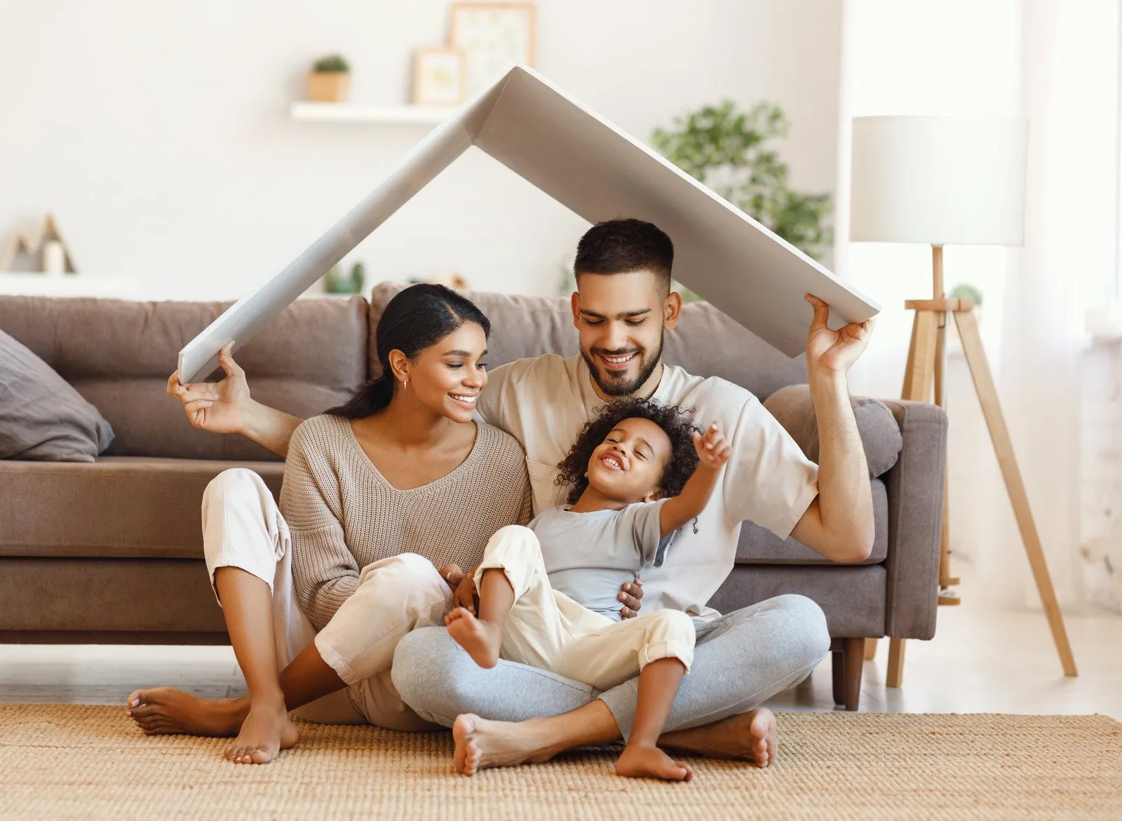 a family of four smiling while they pose beneath the cardboard cutout of a home roof