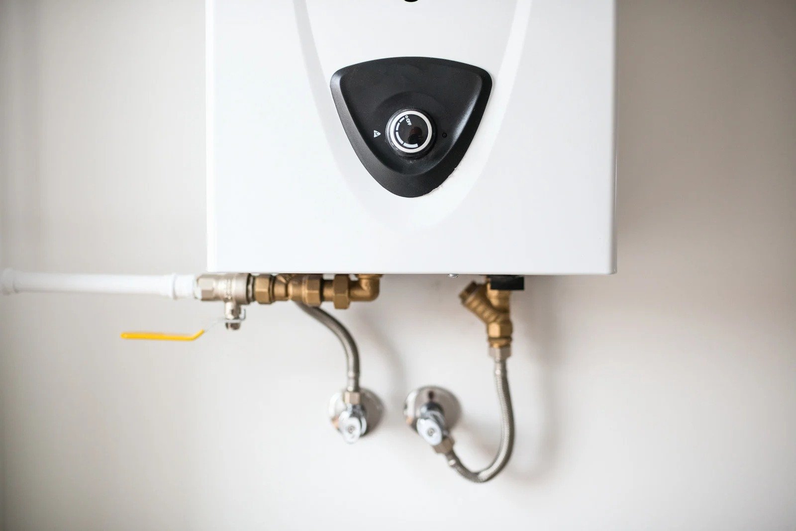 a white water heater mounted on a wall in a well lit room